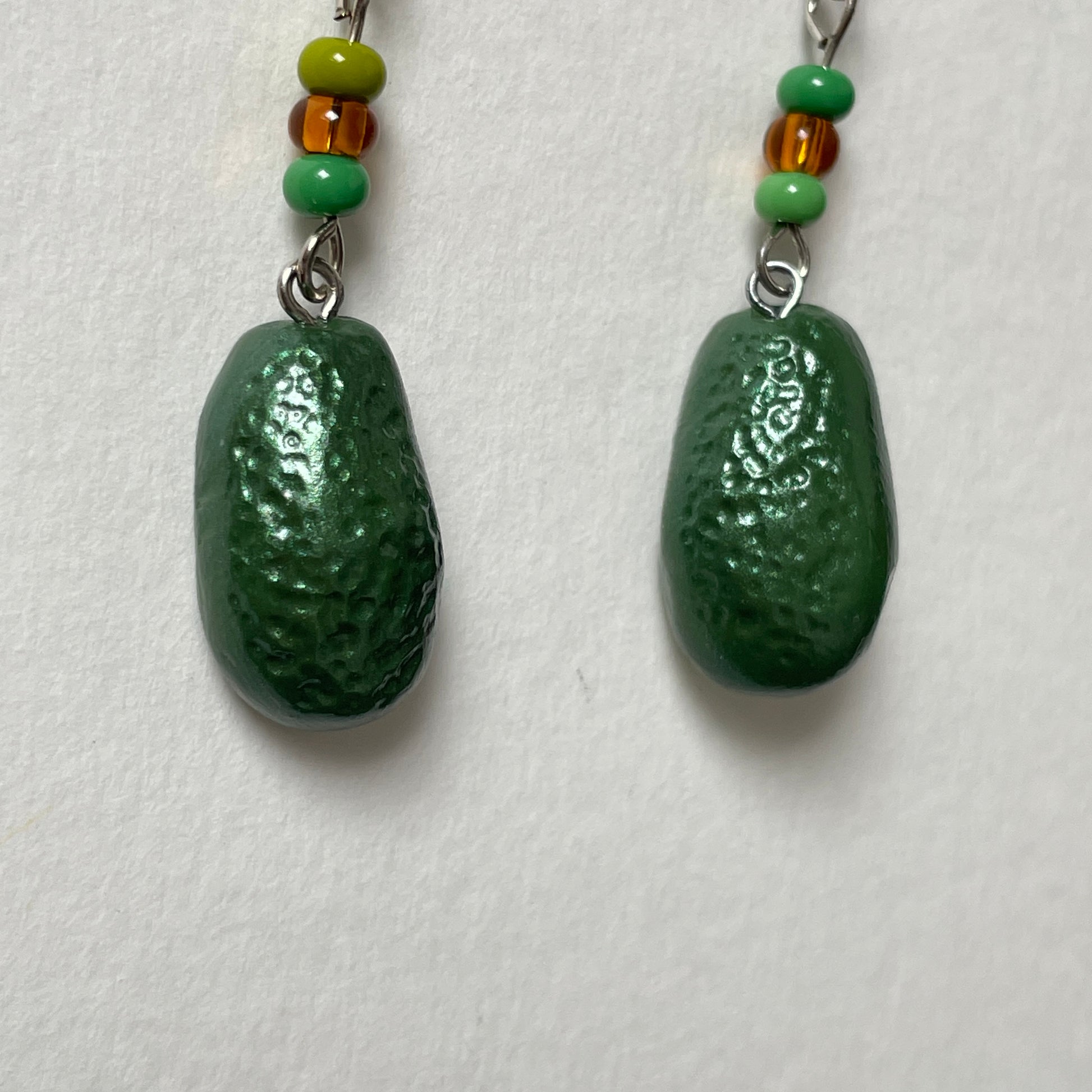 Avocado-shaped earrings with green and brown beads on a white background