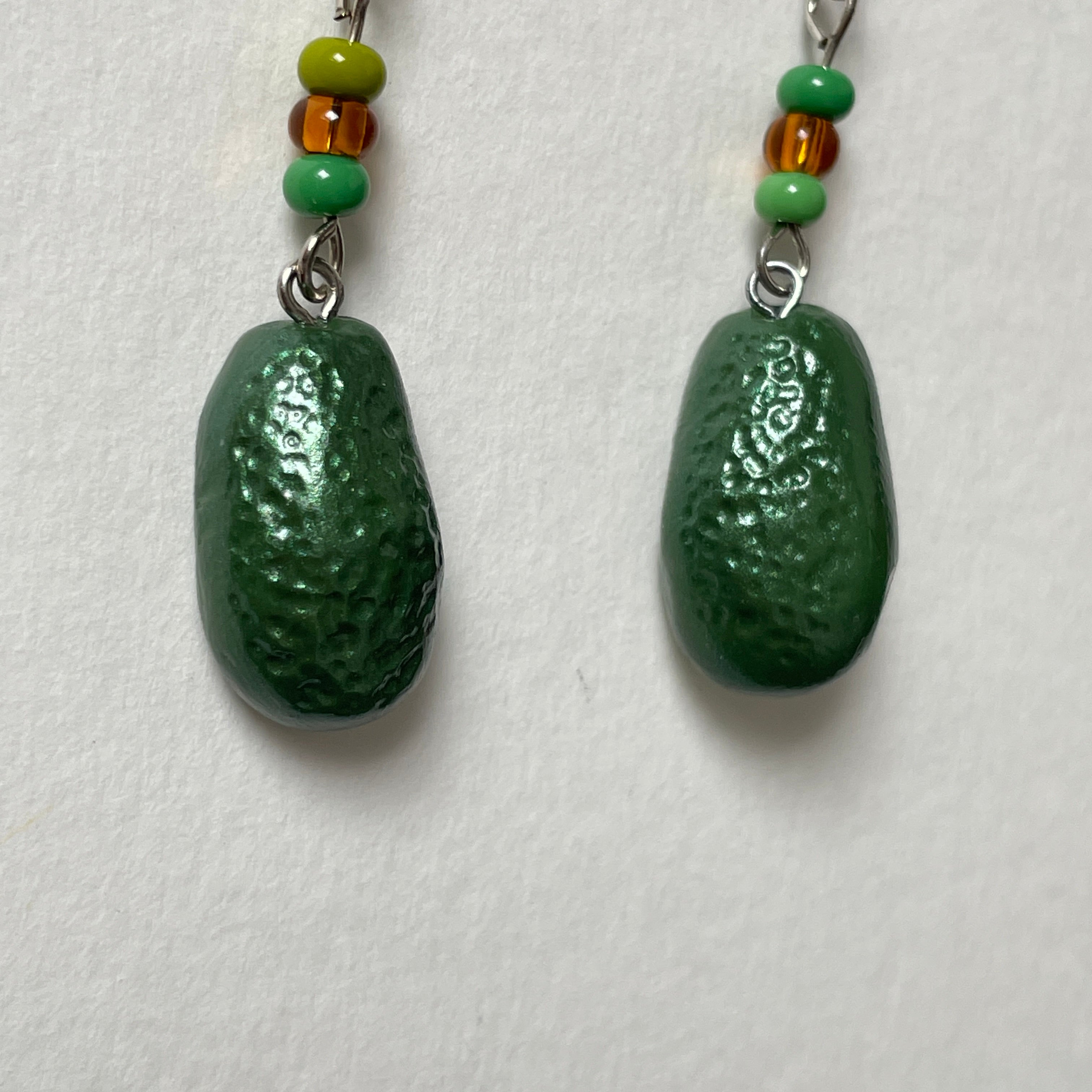 Avocado-shaped earrings with green and brown beads on a white background