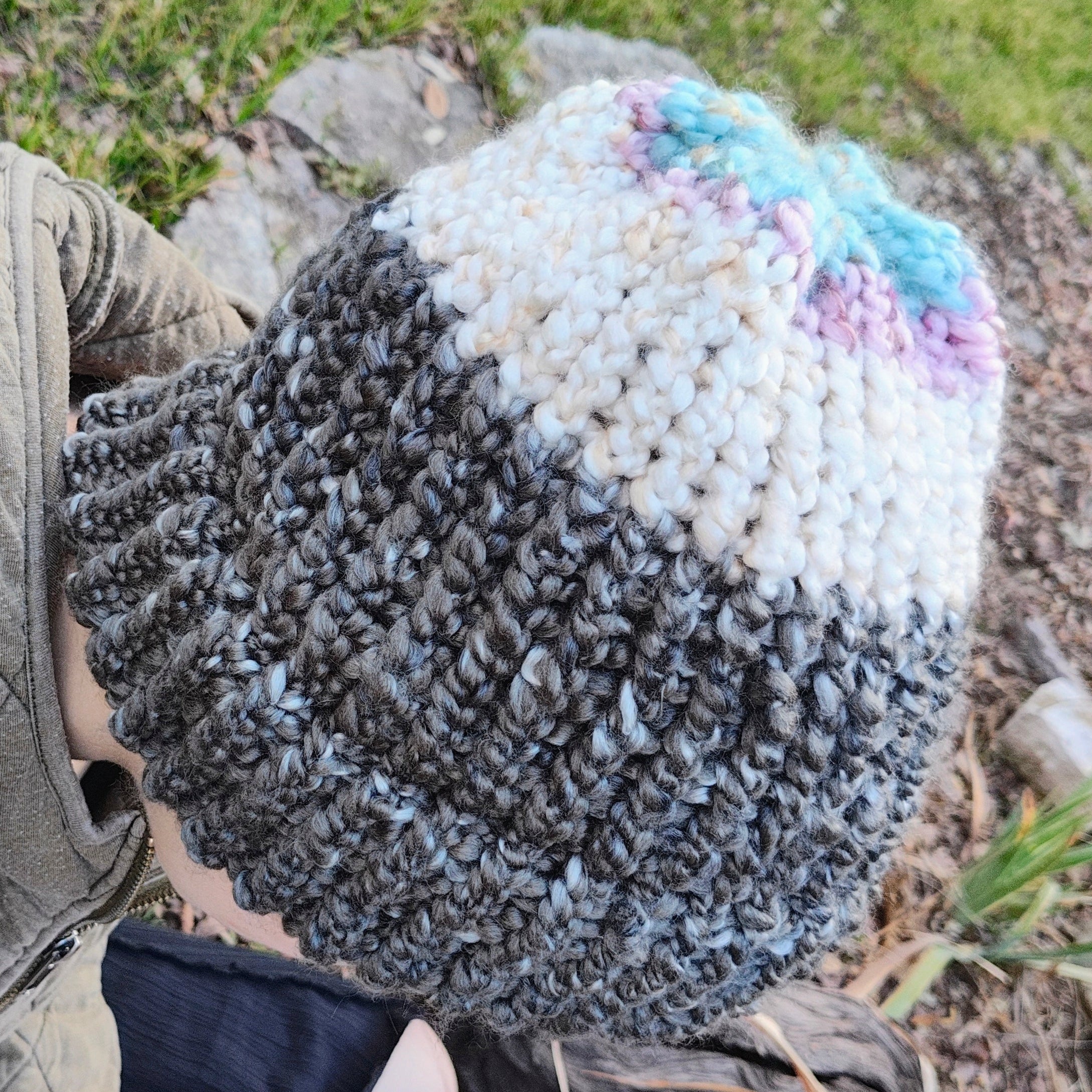 Person wearing a colorful knit beanie outdoors on a grassy area.