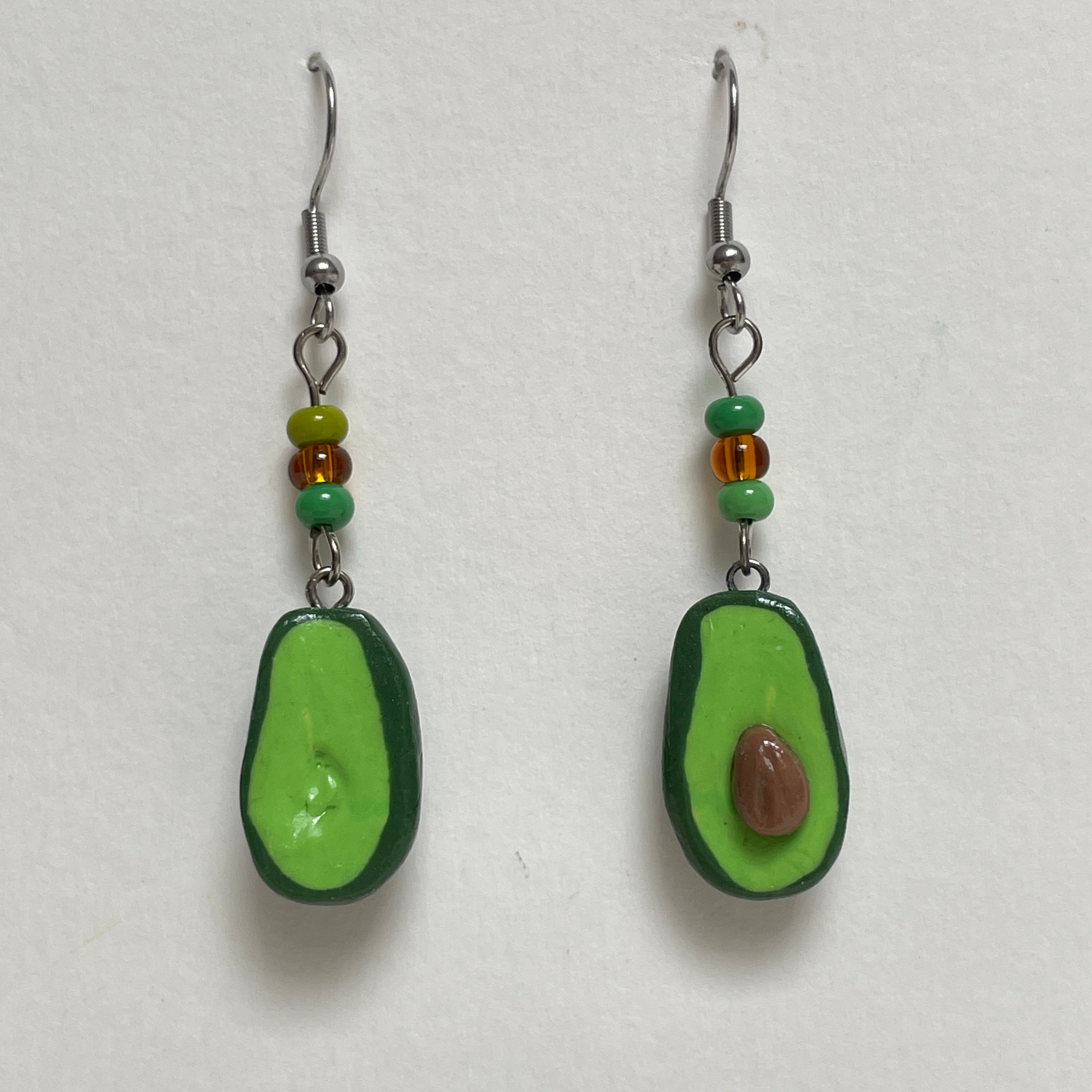 Avocado-shaped earrings with green and brown beads on a white background