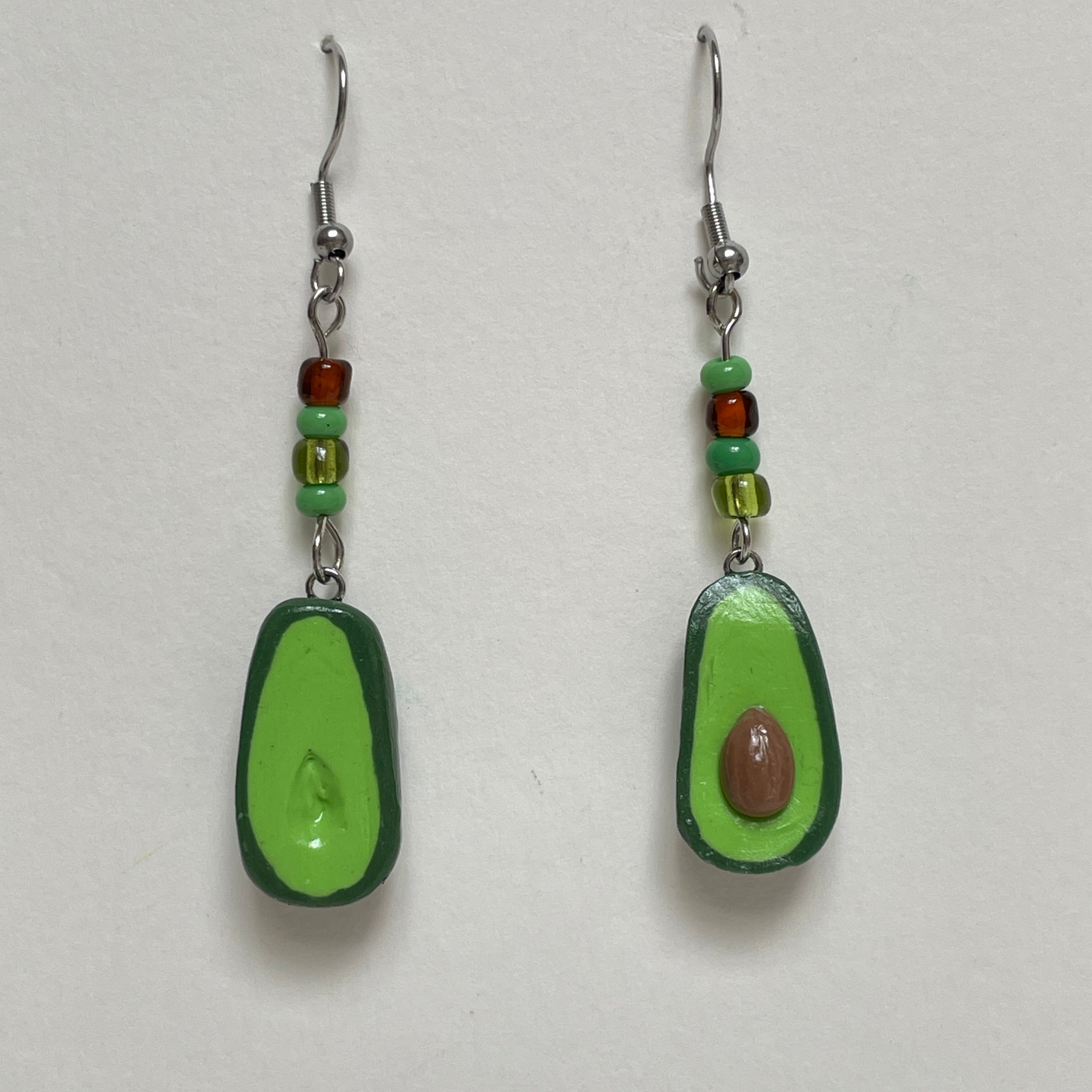 Avocado-shaped earrings with green and brown details on a white background